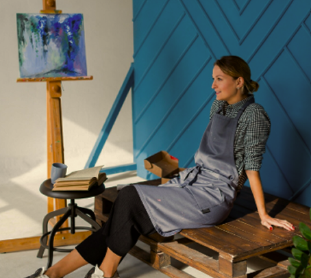Woman sitting on a wooden bench beside an easel in an art studio
