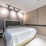 Bedroom with a dark quilted upholstered headboard and ceiling track lights