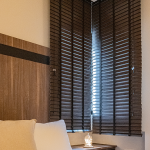 Bedroom corner featuring dark timber window blinds and a vertical timber wall panel