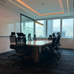 Boardroom with an oval table, black chairs and cove lighting