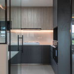 Kitchen behind a glass sliding partition with dark cabinets