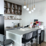 Kitchen with a white island counter, bar stools, pendant lights and open shelving