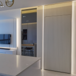 Kitchen island beside white fluted tall cabinets with LED strip lighting