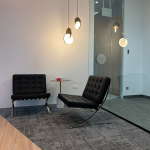 Office lounge area with black leather chairs and pendant lights