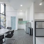 Office pantry with white cabinets beside glass partitions