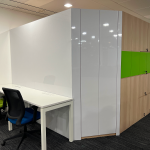 Office workstation with white partition panels and a green pin board