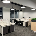 Open-plan office with white desks, pendant lights and storage cabinets