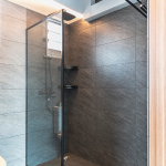 Shower area with a glass screen and dark stone-look tiles