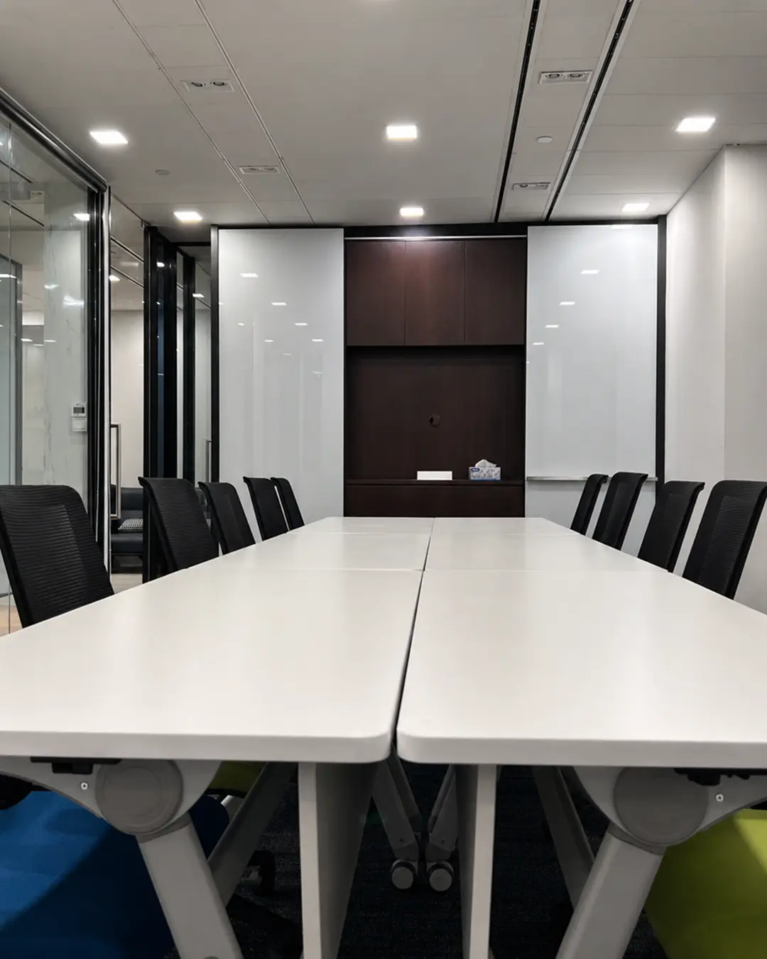 Modern open-plan office fit-out with white workstations, black chairs and planter dividers